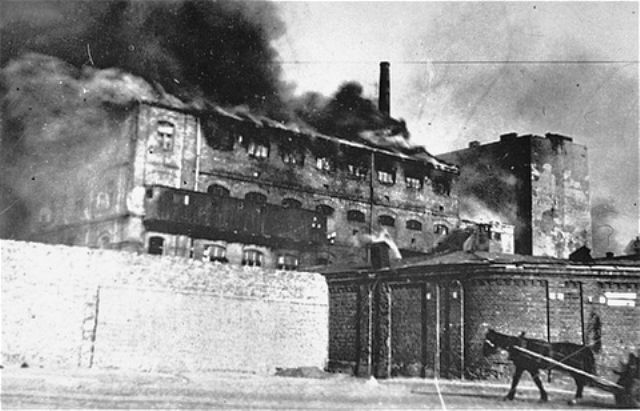 A factory razed by the SS burns during the suppression of the Warsaw ghetto uprising